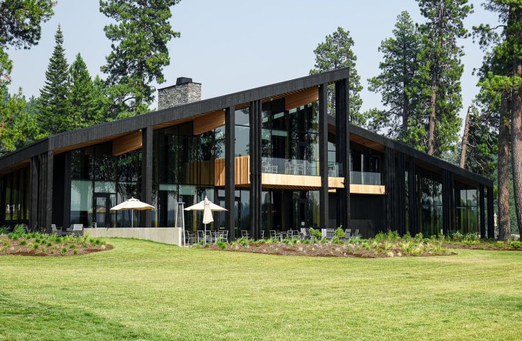 large black building with green lawn and pine trees in the background