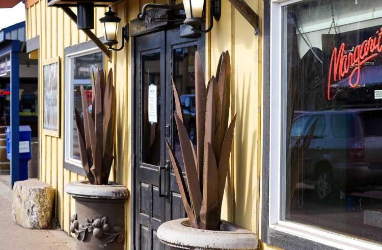 front doors of a restaurant with a neon margarita sign