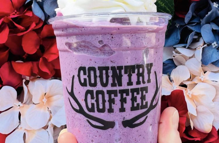 purple smoothie in a to go cup, colorful flowers in the background