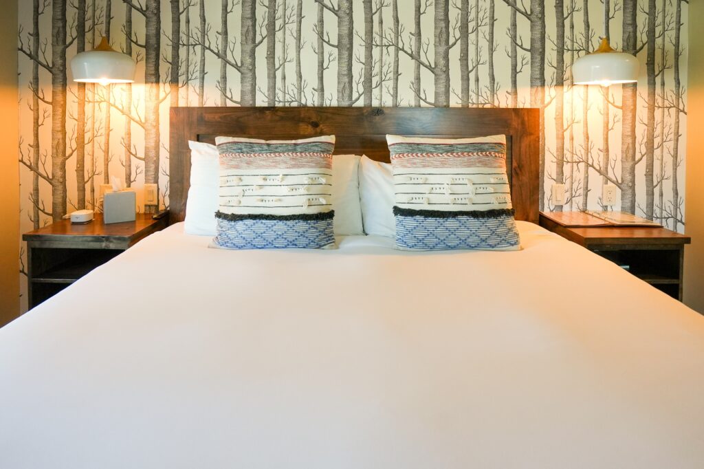 hotel bed with lamps and tree wallpaper