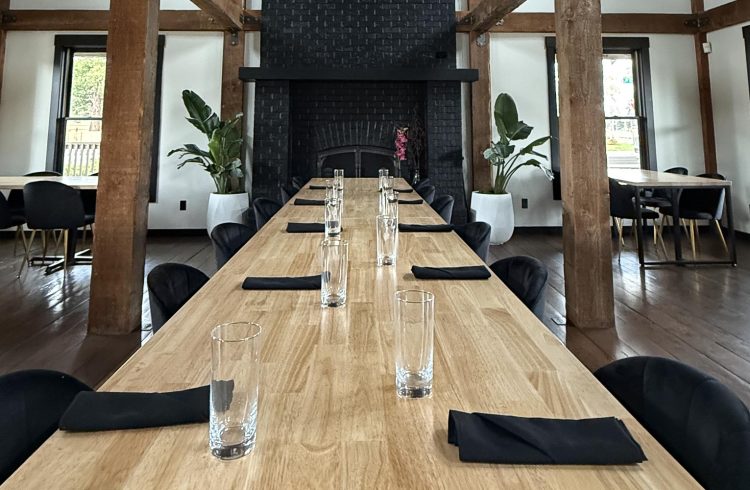 long wood table with place settings and fireplace in a restaurant