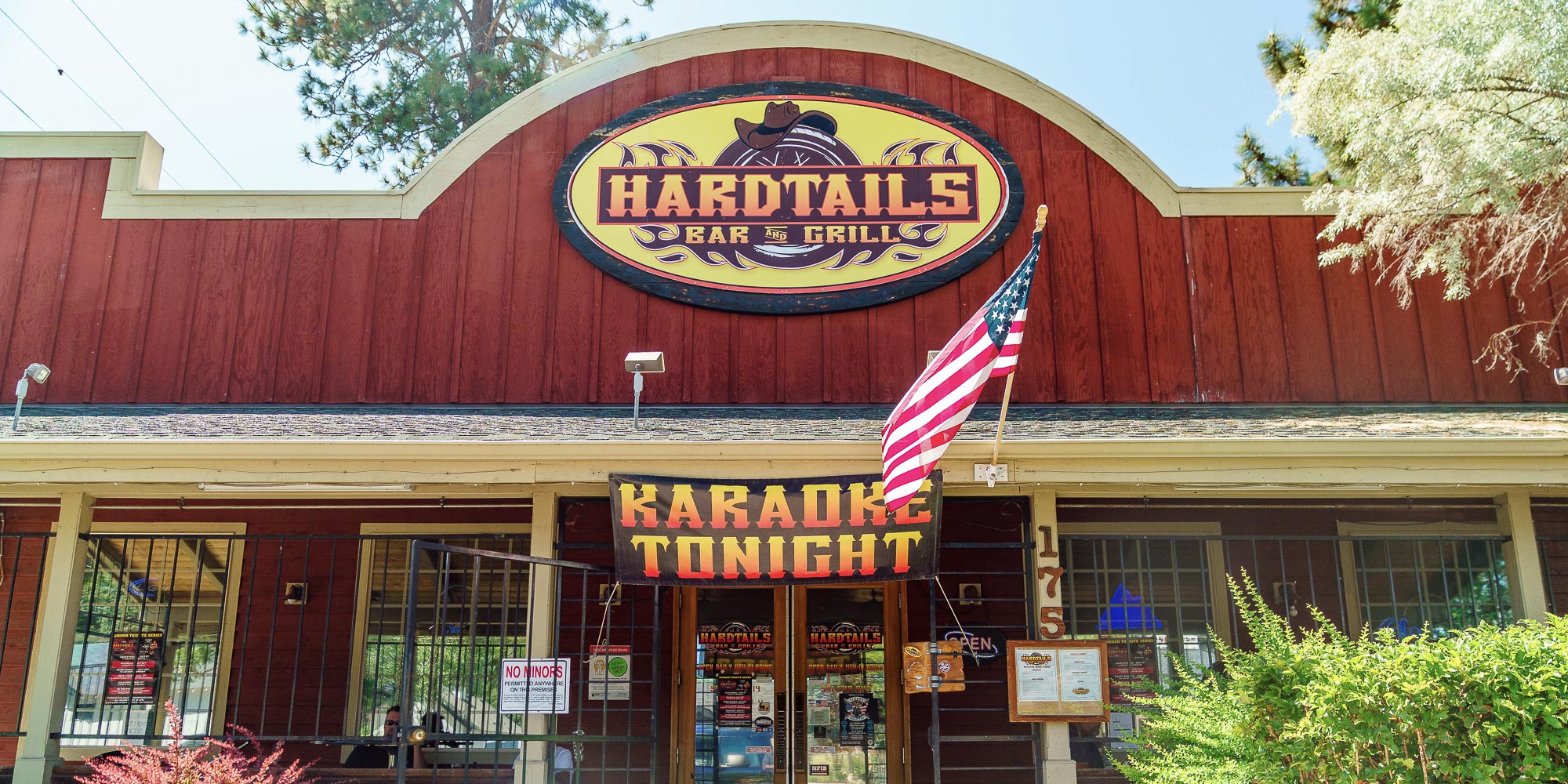 front door at hardtails bar with landscaping and an American Flag